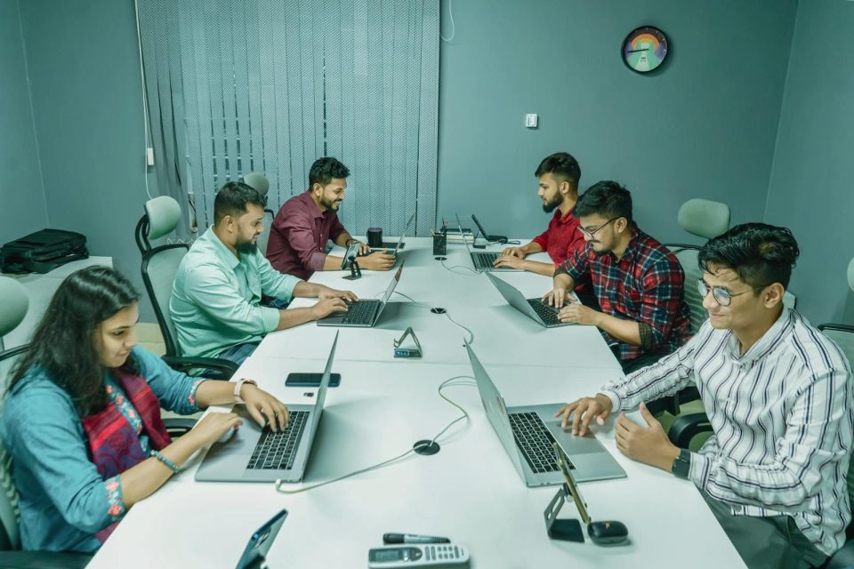 A group of professionals working together on laptops in a modern office setting.