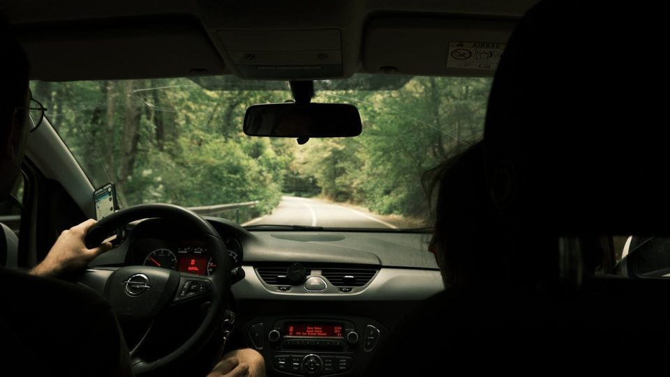 View from inside a car driving through a lush green forest on a serene day.